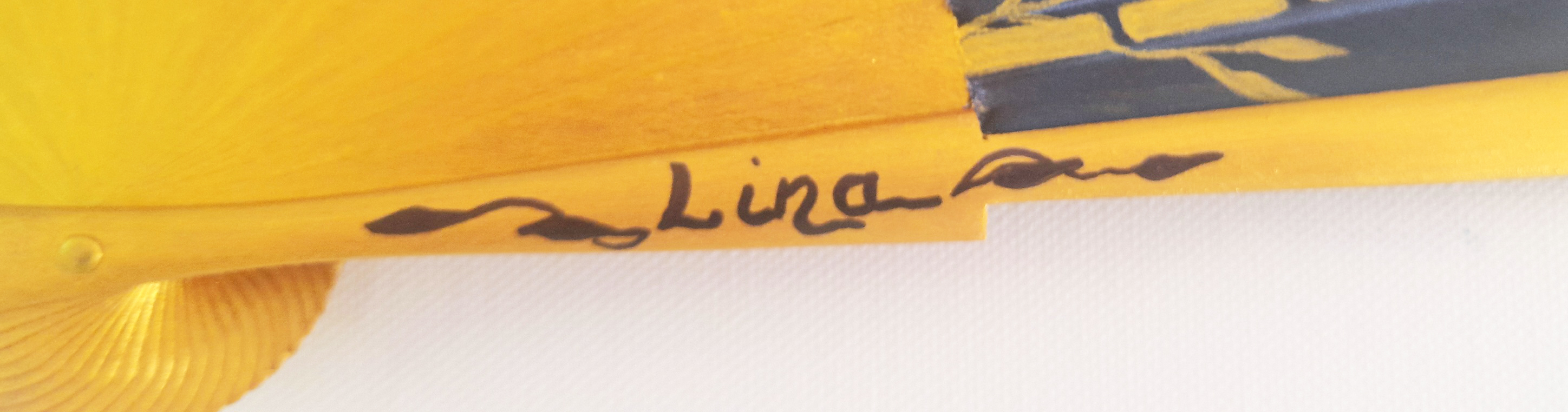 Signature artisanale sur une branche en bois d'éventail peint.