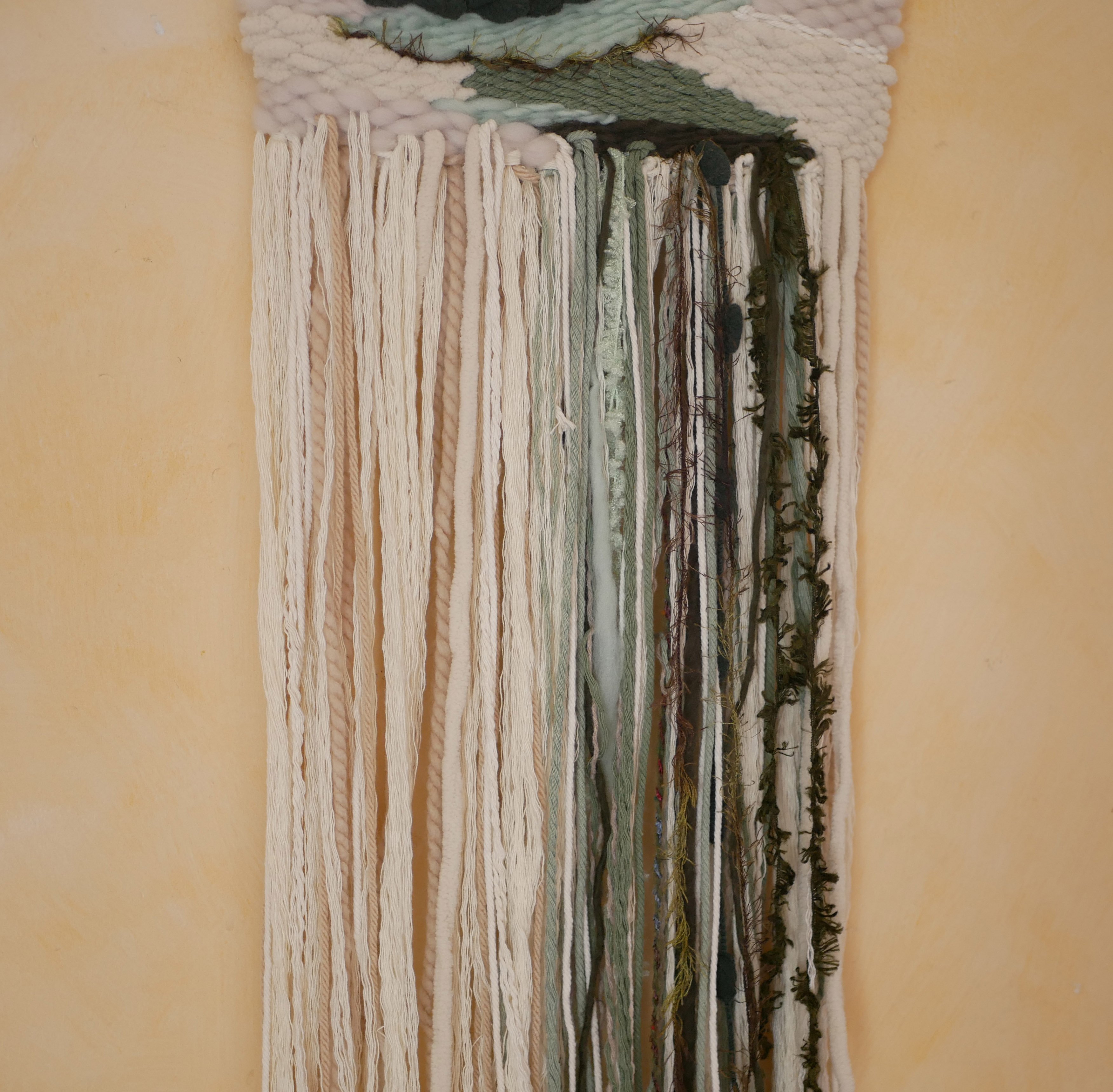 Suspension tissage mural "Les rivi&egrave;res v&eacute;g&eacute;tales" en laines et coton de couleurs vert d'eau et longues franges