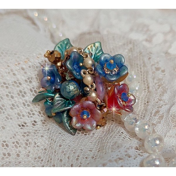 Bague Bel Air mont&eacute;e avec des fleurs lucites peintes &agrave; la main aux couleurs : Bleu, Rose, Rouge, Argent, Blanc avec feuilles ondul&eacute;es Vert Cuivr&eacute; &agrave; laquelle s&rsquo;ajoute perles Dor&eacute;es en Verre