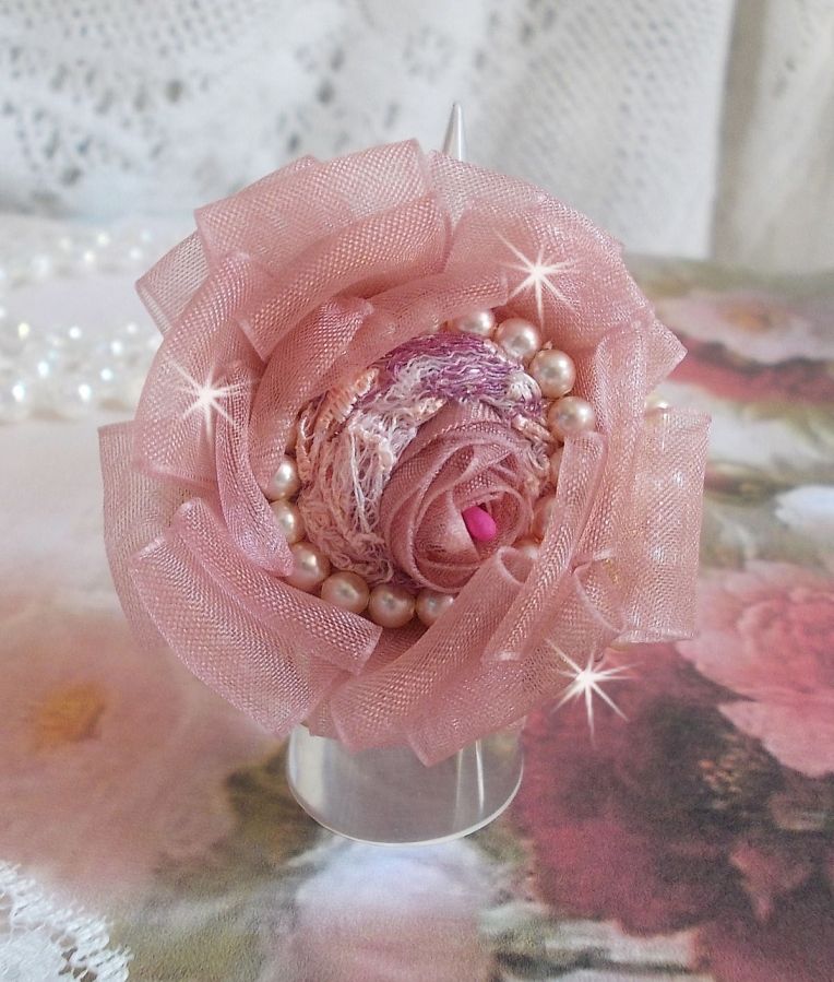 Der Ring Douceur Poudrée Haute-Couture wurde mit feinster Spitze, Organzaband Vieux Rose Antique, Swarovski-Kristallen und Miyuki Rocailles kreiert.