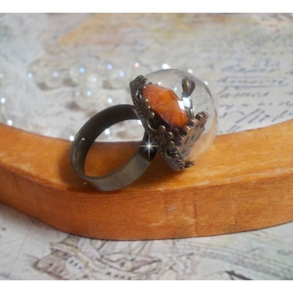 Bague Majest&eacute; Steampunk aux rouages m&eacute;caniques &agrave; laquelle s&rsquo;ajoute une cl&eacute; et un strass de couleur Siam et un strass en verre Dor&eacute;. Le tout est mis sous un globe en verre sur une bague r&eacute;glable laiton