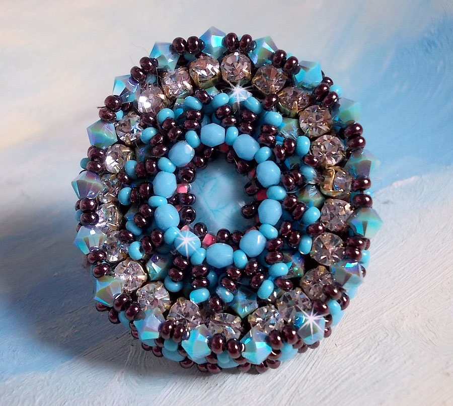 Bestickter Naïade Ring mit einem Cabochon in türkisblauem Harz und Kristall, ein schönes Lichtspiel.