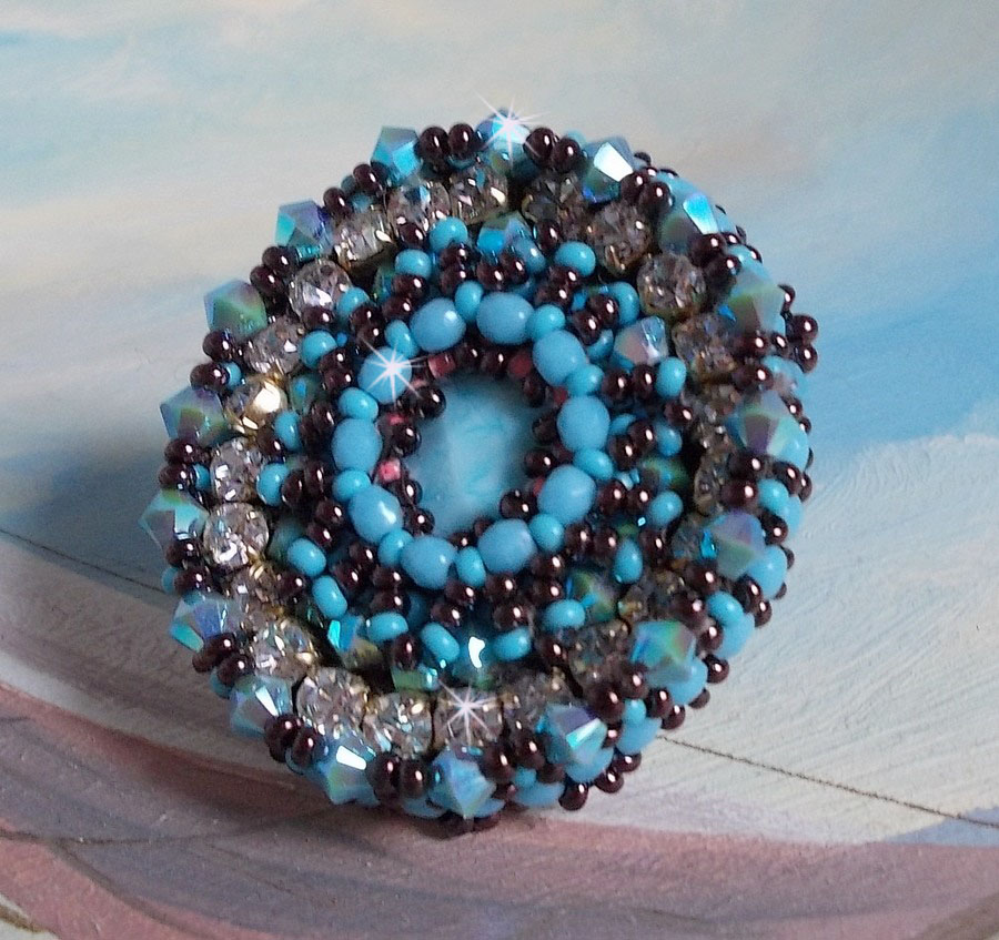 Bestickter Naïade Ring mit einem Cabochon in türkisblauem Harz und Kristall, ein schönes Lichtspiel.