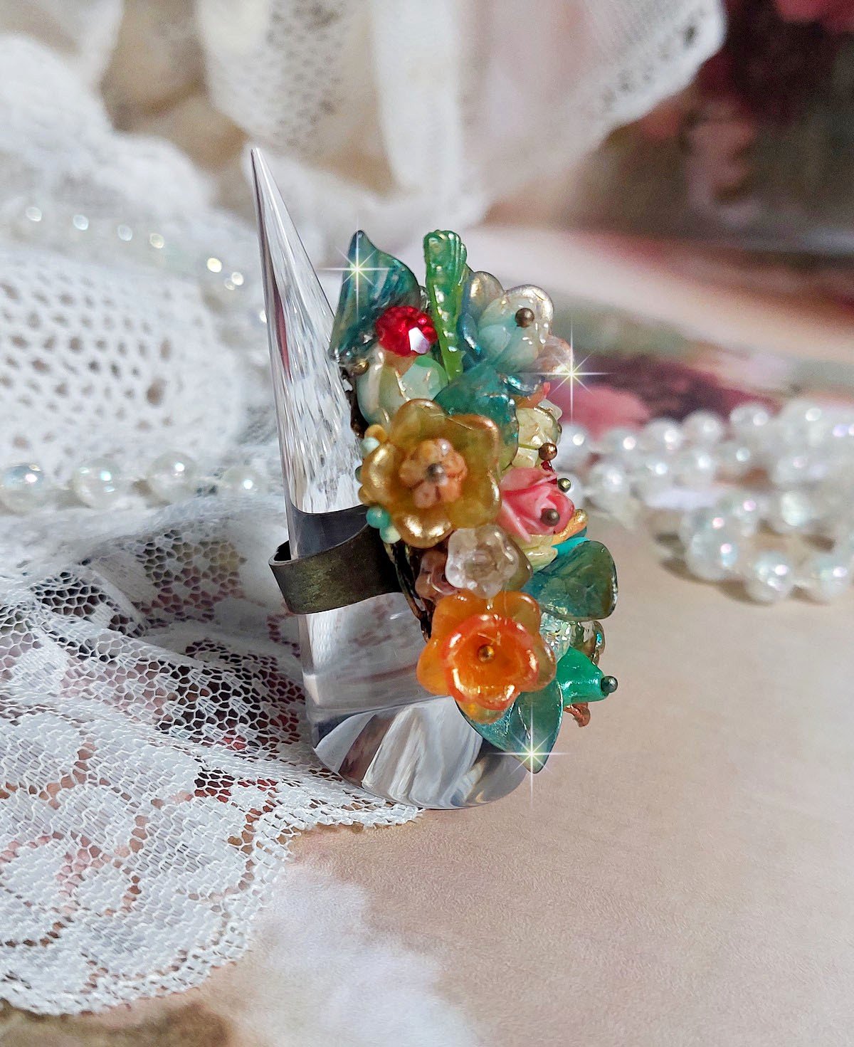 Bague Patiflo d&rsquo;une composition florale cr&eacute;&eacute;e avec des cristaux, fleurs en R&eacute;sine, perles, clochettes, pens&eacute;es, boutons de rose en Verre, estampes et coupelles. Le tout est mont&eacute; sur une bague estampe