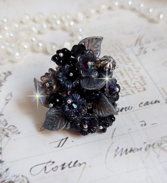 Bague Soir de Lune cr&eacute;&eacute;e avec des fleurs lucites Noires et Grises peintes &agrave; la main, cristaux, perles en r&eacute;sine, perles en verre et coupelle argent&eacute;e. Le tout est mont&eacute; sur une bague argent&eacute;e