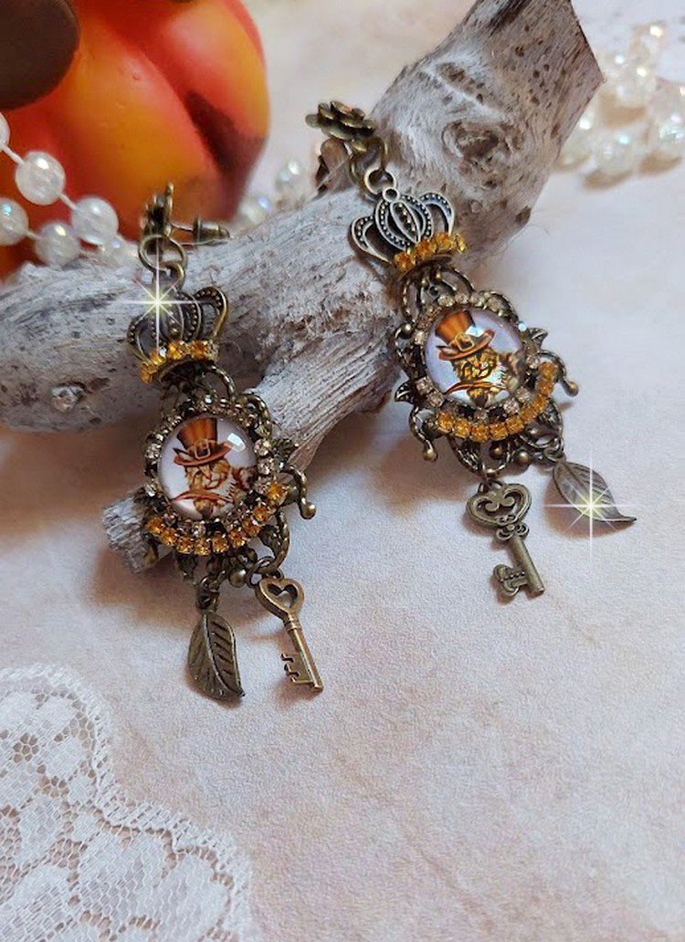 BO Chatibo Steampunk montées avec cabochons ronds en verre représentant un chat chapeauté Haute de Forme Orange. Strassées avec une couronne, breloques clés et feuilles. Montées sur clips Bronze