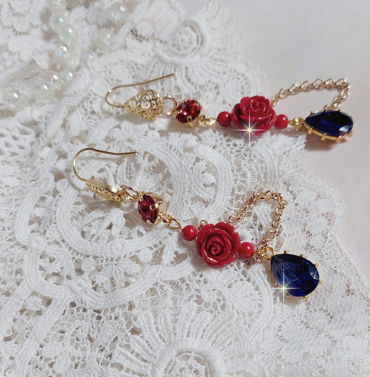 BO Flamenca montées avec des cabochons en Cristal et des roses en Résine aux couleurs Rouges à laquelle s’ajoute des perles rondes en Jade, une chaîne avec des poires en oxyde de Zirconium