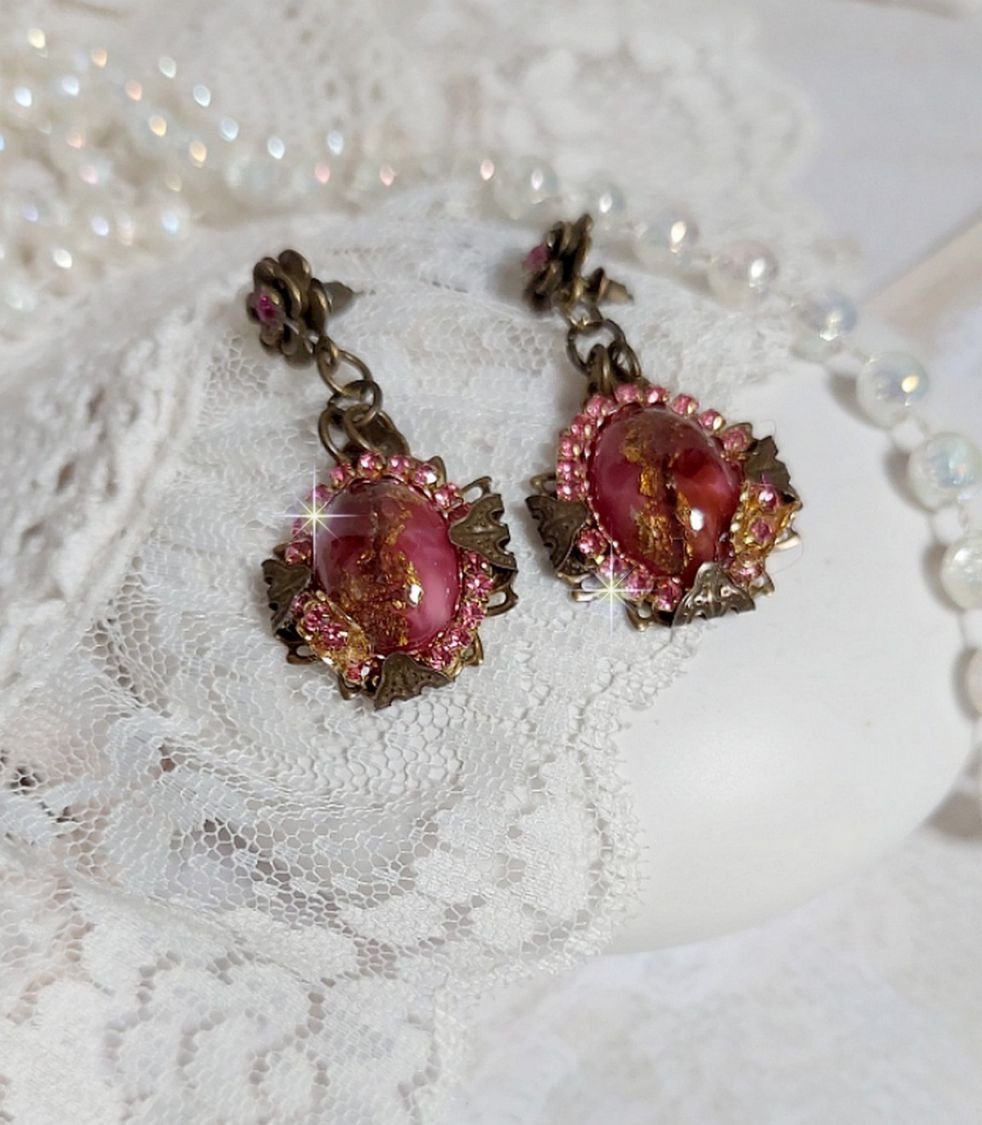 BO Pampelone Fuchsia avec cabochons ovales aux feuilles d’or ornées de strass, cristaux, Roses et breloques papillons. Montées sur des estampes carrées et des clous d’oreilles Bronze en Métal