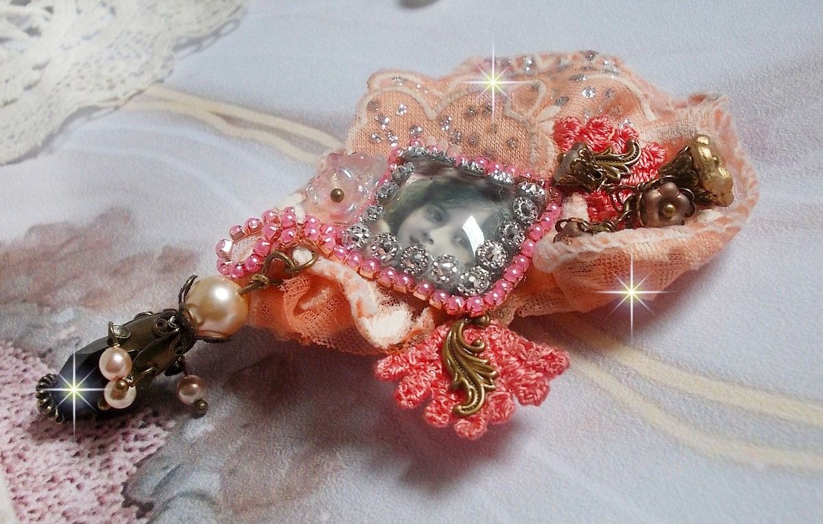 Rustic Rose Brosche mit einem Cabochon, der ein lächelndes Mädchen darstellt, orangefarbener Strass- und Rosenspitze, Kristallen, Glasperlen und verschiedenen Accessoires.