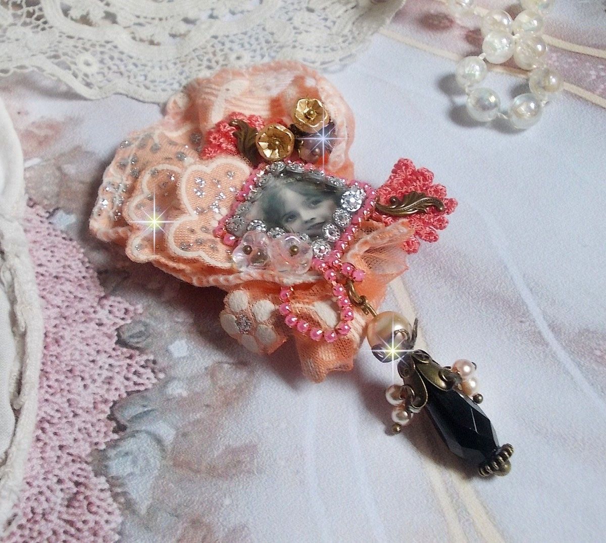 Rustic Rose Brosche mit einem Cabochon, der ein lächelndes Mädchen darstellt, orangefarbener Strass- und Rosenspitze, Kristallen, Glasperlen und verschiedenen Accessoires.