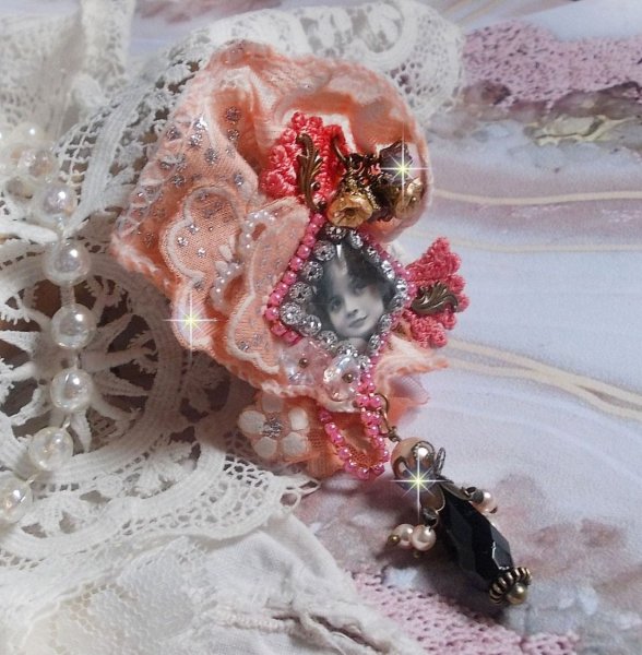Rustic Rose Brosche mit einem Cabochon, der ein l&auml;chelndes M&auml;dchen darstellt, orangefarbener Strass- und Rosenspitze, Kristallen, Glasperlen und verschiedenen Accessoires.