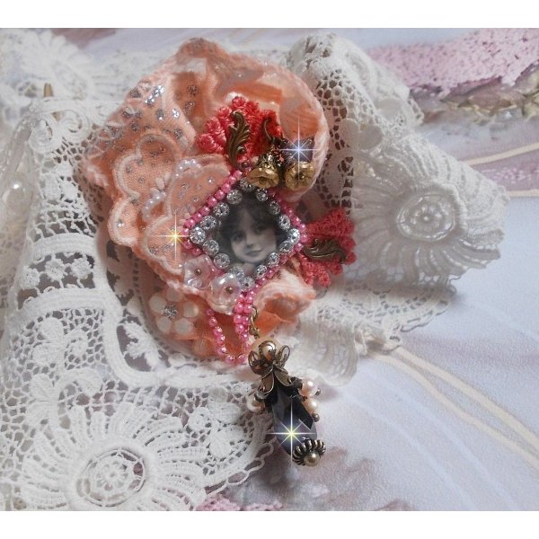 Rustic Rose Brosche mit einem Cabochon, der ein l&auml;chelndes M&auml;dchen darstellt, orangefarbener Strass- und Rosenspitze, Kristallen, Glasperlen und verschiedenen Accessoires.