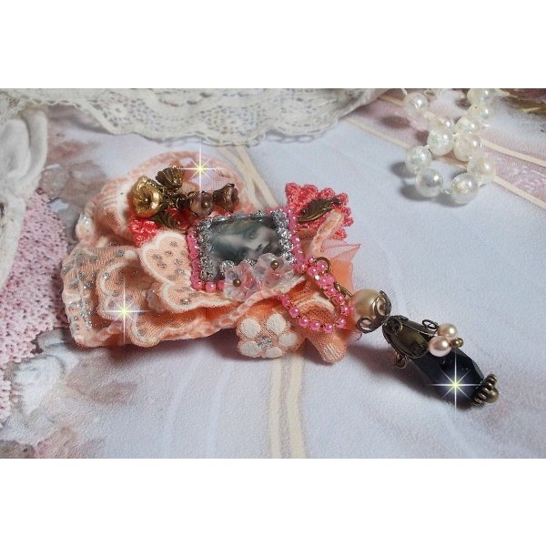 Rustic Rose Brosche mit einem Cabochon, der ein l&auml;chelndes M&auml;dchen darstellt, orangefarbener Strass- und Rosenspitze, Kristallen, Glasperlen und verschiedenen Accessoires.