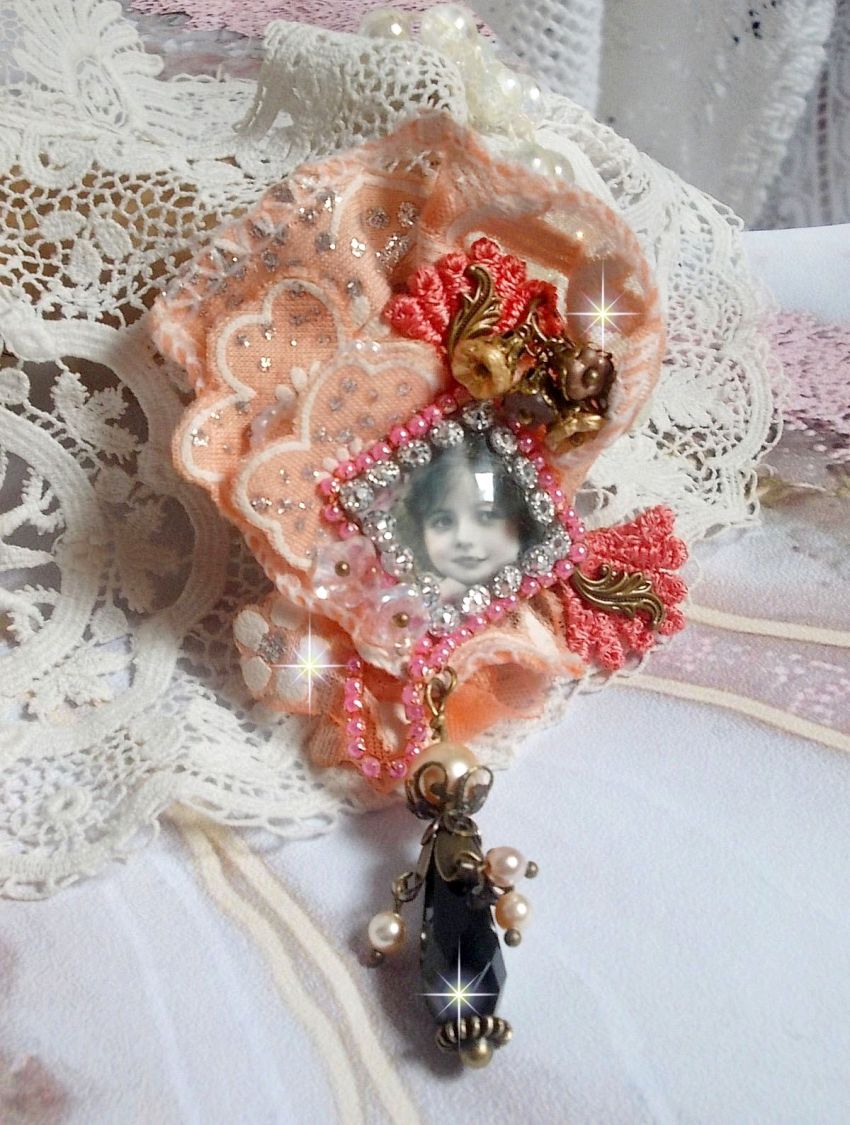 Rustic Rose Brosche mit einem Cabochon, der ein lächelndes Mädchen darstellt, orangefarbener Strass- und Rosenspitze, Kristallen, Glasperlen und verschiedenen Accessoires.