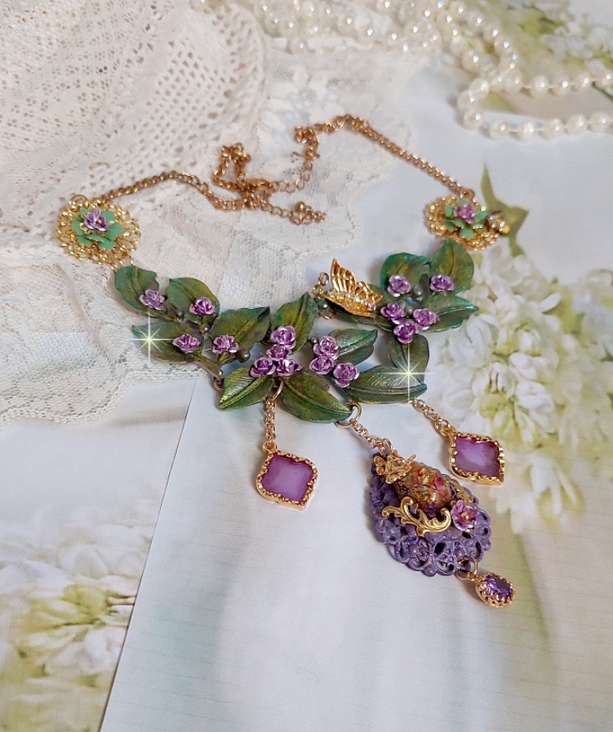 Collier Cam&eacute;lia Japonica mont&eacute; avec un motif feuilles aquarell&eacute;s &agrave; la main, paillettes, breloques papillons et abeille, roses m&eacute;tal, cabochon cristal, pendentifs &eacute;poxy aux couleurs d&rsquo;arc en ciel