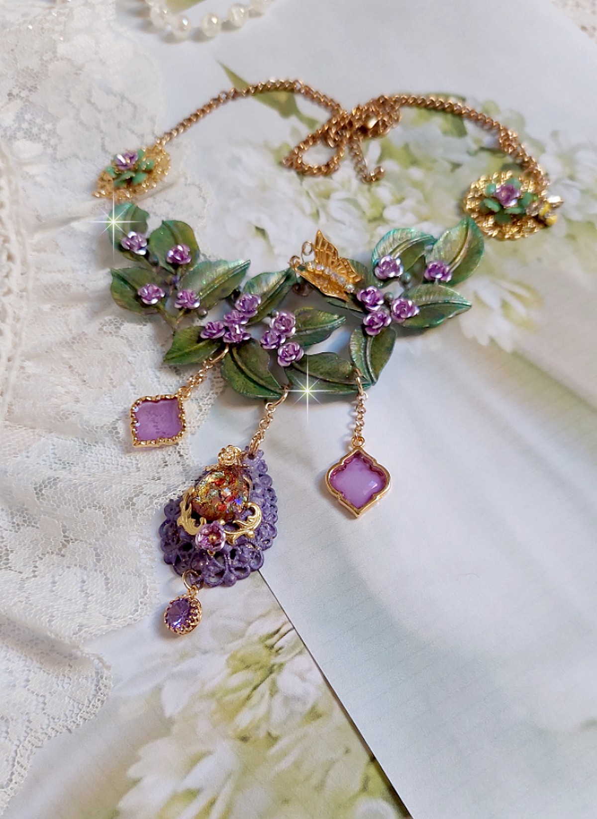 Collier Camélia Japonica monté avec un motif feuilles aquarellés à la main, paillettes, breloques papillons et abeille, roses métal, cabochon cristal, pendentifs époxy aux couleurs d’arc en ciel