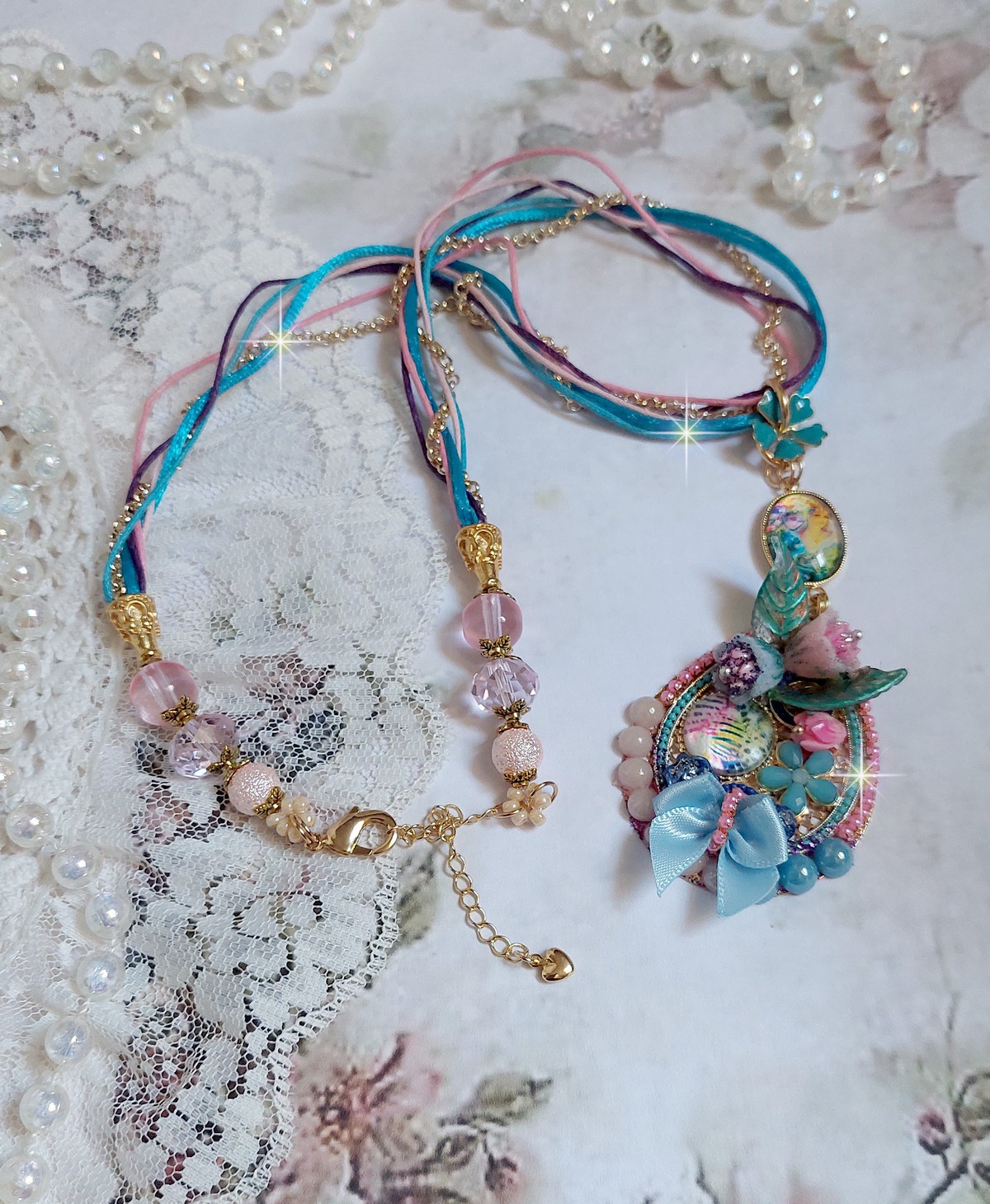  Collier Coquette créé avec deux estampes à laquelle s’ajoute des fleurs en velours floqué, perles aplaties Cristal, fleurs : Epoxy, Porcelaine, Résine, cabochon loupe, rubans et chaîne plaqué Or