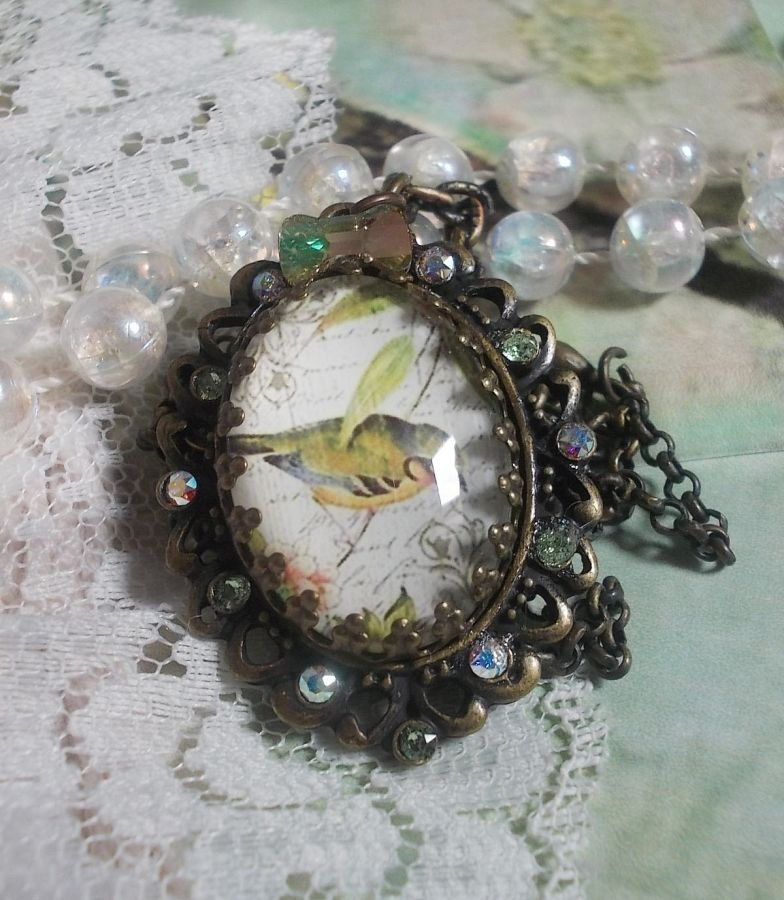 Gartenvogel-Halskette mit einem Lupen-Cabochon und Kristallen auf bronzefarbenen Accessoires.