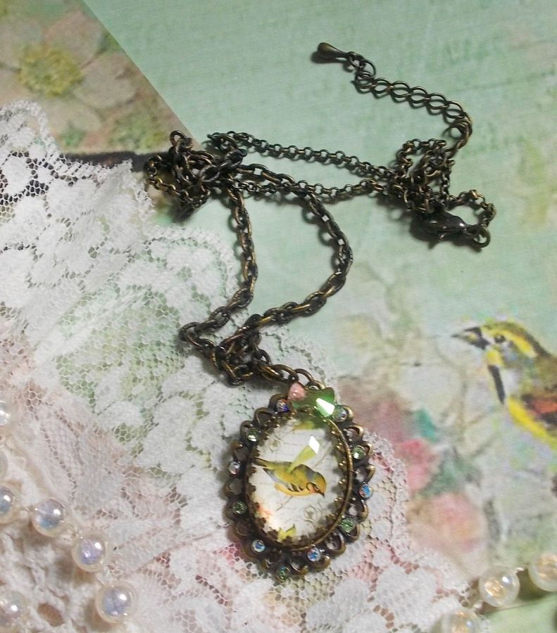 Gartenvogel-Halskette mit einem Lupen-Cabochon und Kristallen auf bronzefarbenen Accessoires.
