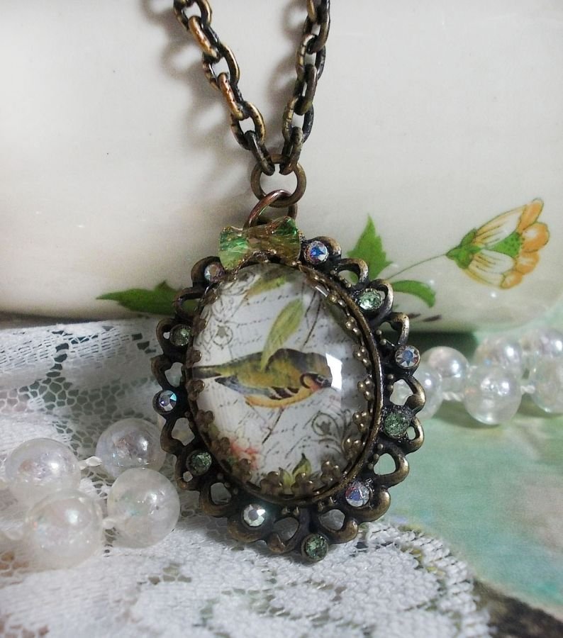 Gartenvogel-Halskette mit einem Lupen-Cabochon und Kristallen auf bronzefarbenen Accessoires.
