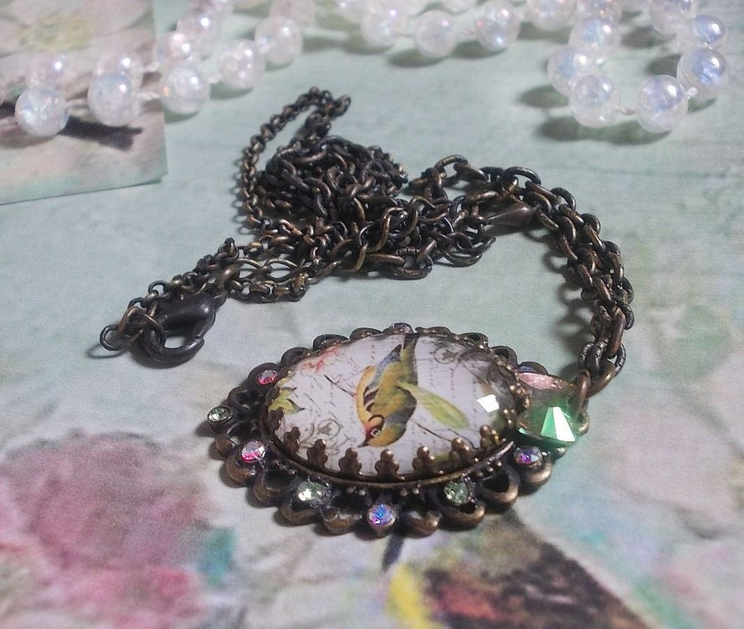 Gartenvogel-Halskette mit einem Lupen-Cabochon und Kristallen auf bronzefarbenen Accessoires.