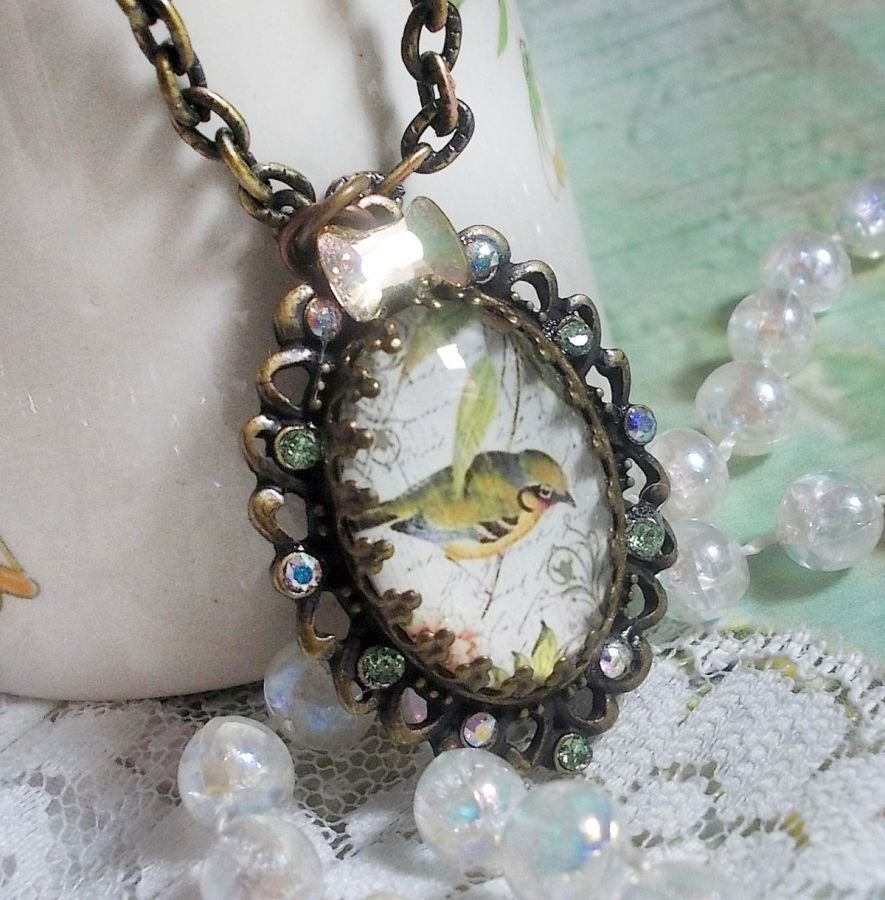 Gartenvogel-Halskette mit einem Lupen-Cabochon und Kristallen auf bronzefarbenen Accessoires.