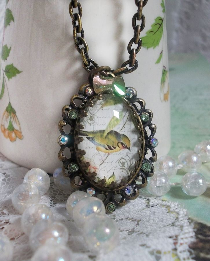 Gartenvogel-Halskette mit einem Lupen-Cabochon und Kristallen auf bronzefarbenen Accessoires.