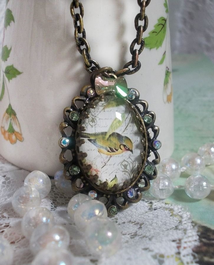 Gartenvogel-Halskette mit einem Lupen-Cabochon und Kristallen auf bronzefarbenen Accessoires.