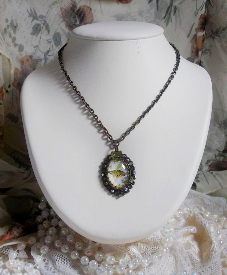 Gartenvogel-Halskette mit einem Lupen-Cabochon und Kristallen auf bronzefarbenen Accessoires.