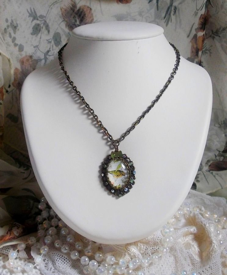 Gartenvogel-Halskette mit einem Lupen-Cabochon und Kristallen auf bronzefarbenen Accessoires.