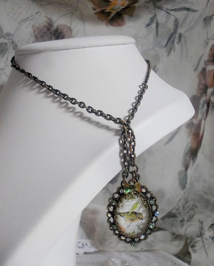 Gartenvogel-Halskette mit einem Lupen-Cabochon und Kristallen auf bronzefarbenen Accessoires.