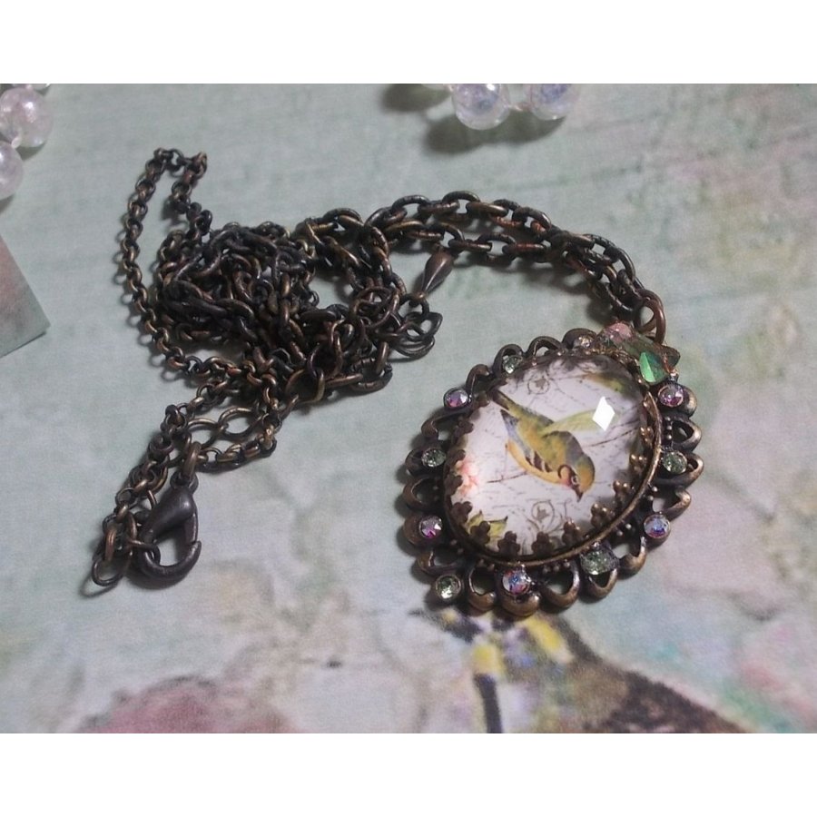 Gartenvogel-Halskette mit einem Lupen-Cabochon und Kristallen auf bronzefarbenen Accessoires.