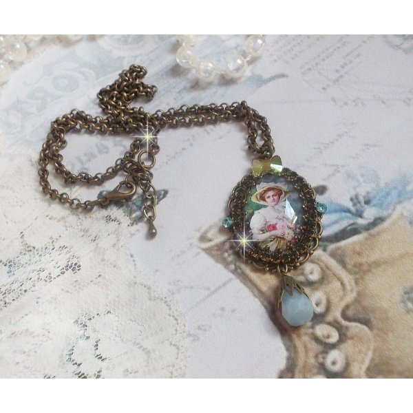 Pendentif Douce Dame cr&eacute;&eacute; avec un cabochon repr&eacute;sentant une femme au chapeau blanc orn&eacute; de cristaux, des accessoires de couleur Bronze et un jade teint&eacute; bleu 