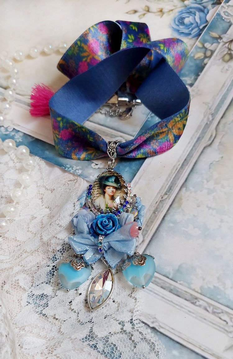 Pendentif Infiniment Bleuté créé avec fleurs synthétiques, résine, cabochon verre, ruban velours et perles Cristal Swarovski