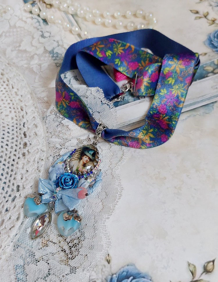 Pendentif Infiniment Bleuté créé avec fleurs synthétiques, résine, cabochon verre, ruban velours et perles Cristal Swarovski