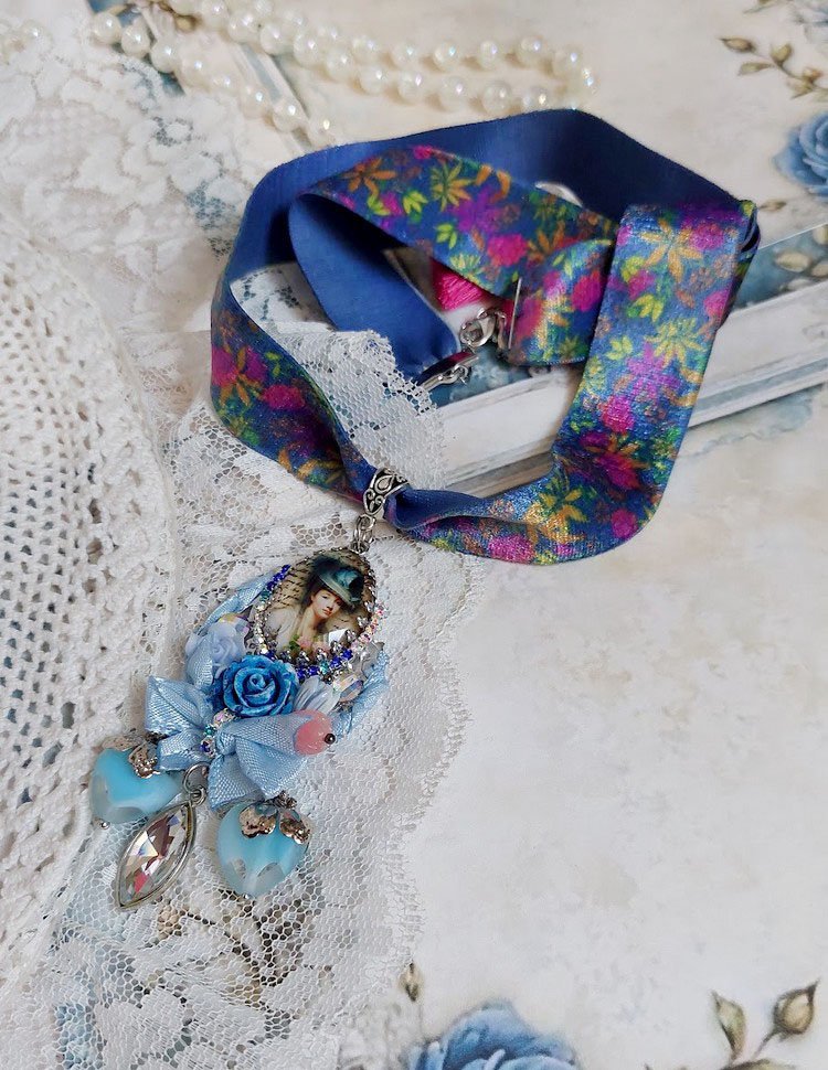 Pendentif Infiniment Bleuté créé avec fleurs synthétiques, résine, cabochon verre, ruban velours et perles Cristal Swarovski