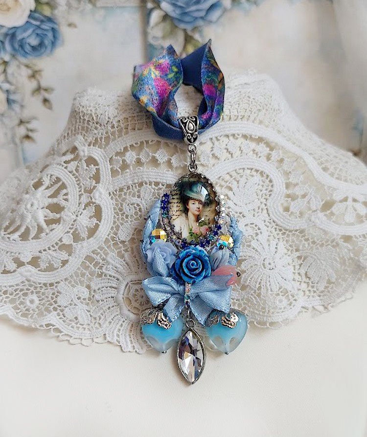 Pendentif Infiniment Bleuté créé avec fleurs synthétiques, résine, cabochon verre, ruban velours et perles Cristal Swarovski