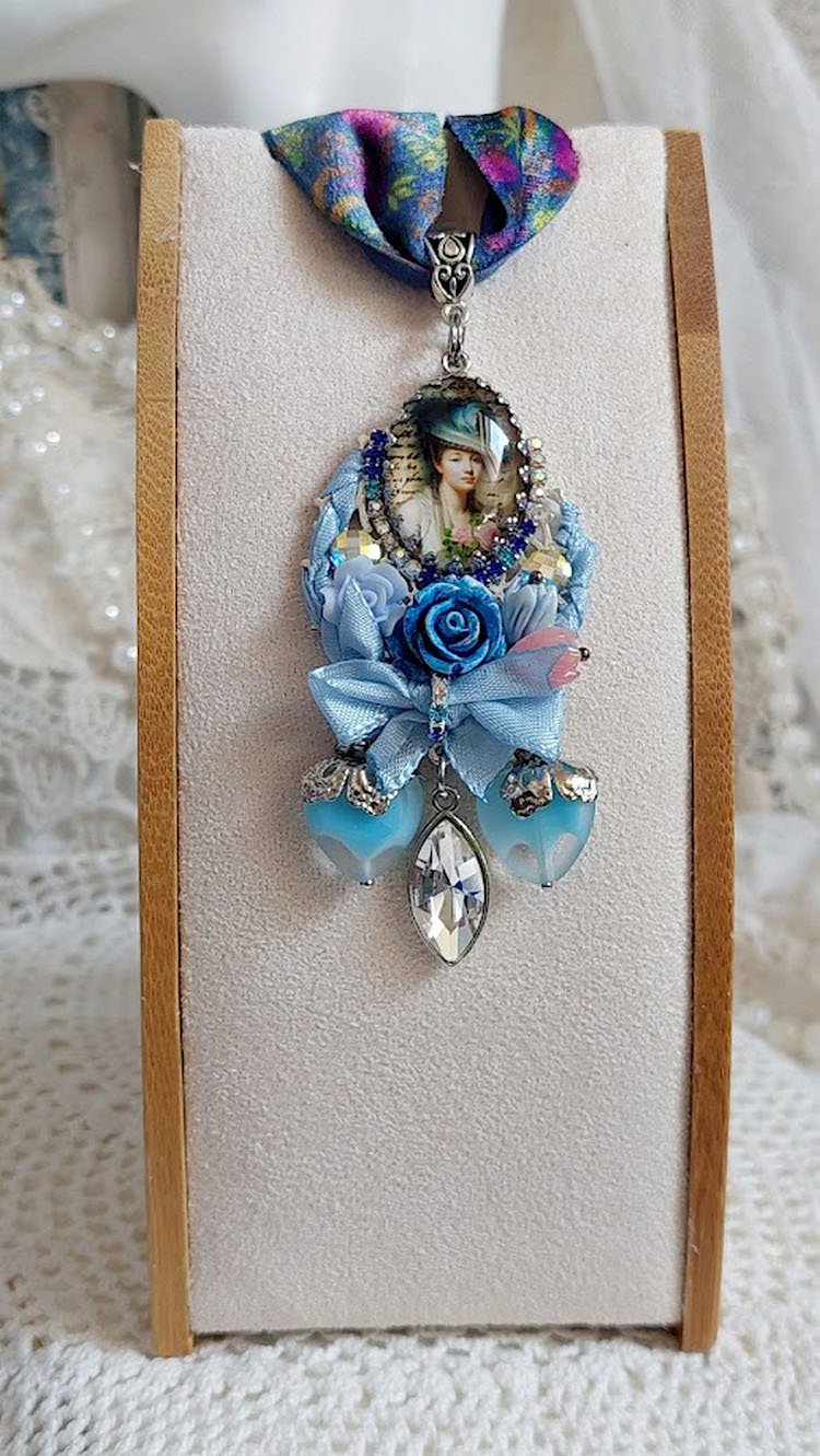 Pendentif Infiniment Bleuté créé avec fleurs synthétiques, résine, cabochon verre, ruban velours et perles Cristal Swarovski