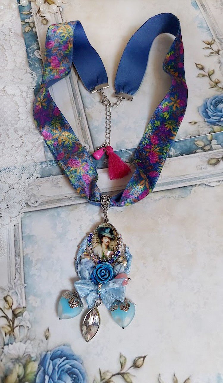 Pendentif Infiniment Bleuté créé avec fleurs synthétiques, résine, cabochon verre, ruban velours et perles Cristal Swarovski
