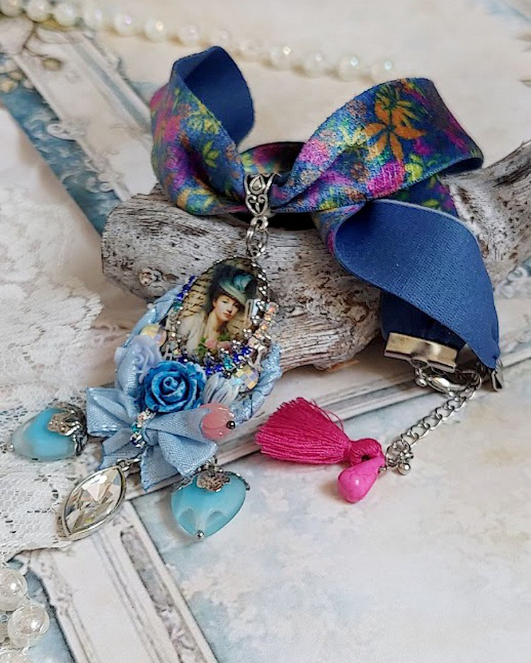 Pendentif Infiniment Bleuté créé avec fleurs synthétiques, résine, cabochon verre, ruban velours et perles Cristal Swarovski