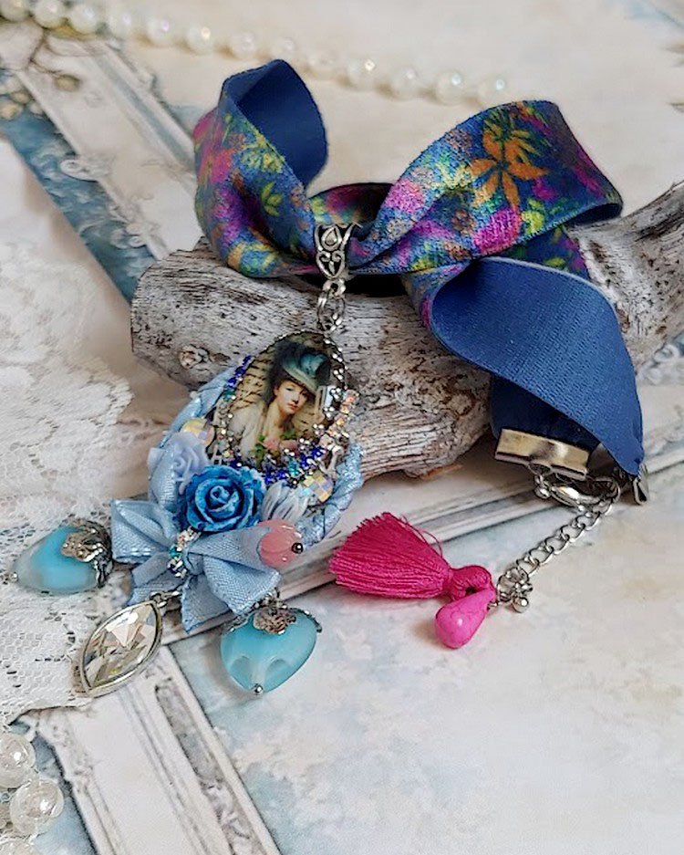 Pendentif Infiniment Bleuté créé avec fleurs synthétiques, résine, cabochon verre, ruban velours et perles Cristal Swarovski