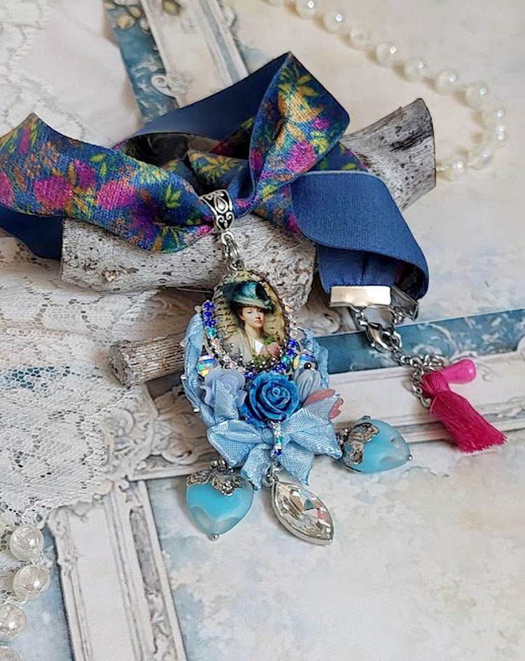 Pendentif Infiniment Bleuté créé avec fleurs synthétiques, résine, cabochon verre, ruban velours et perles Cristal Swarovski