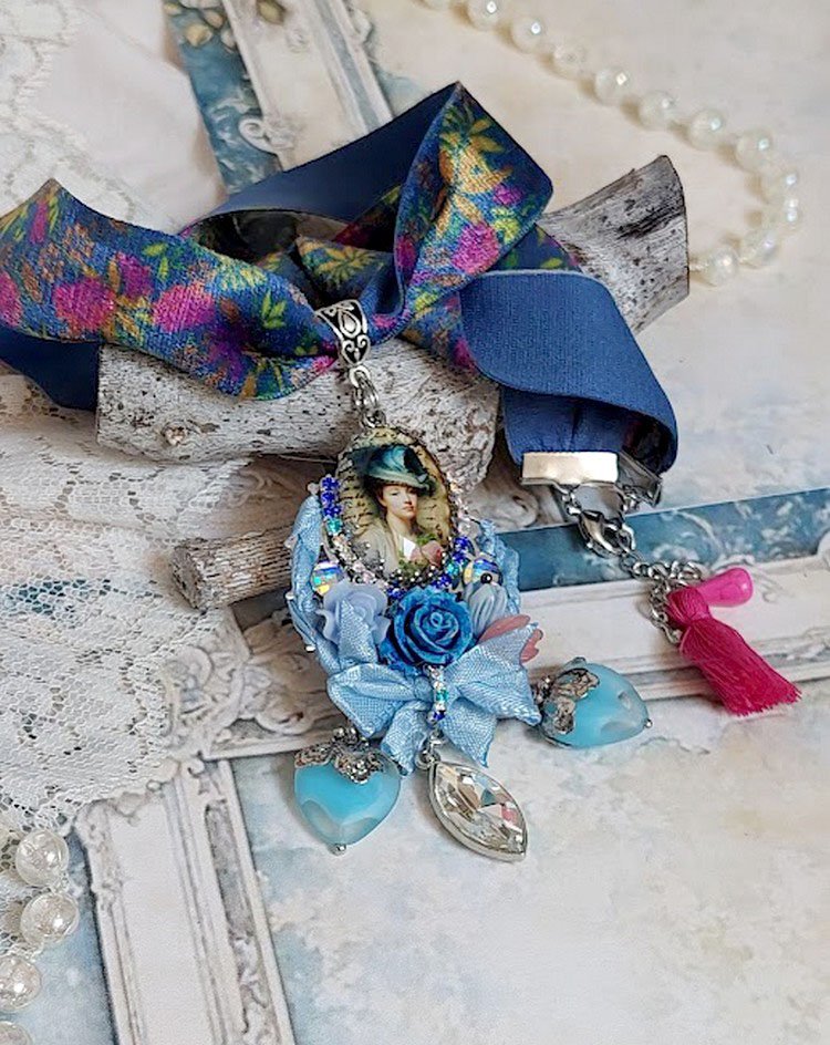 Pendentif Infiniment Bleuté créé avec fleurs synthétiques, résine, cabochon verre, ruban velours et perles Cristal Swarovski