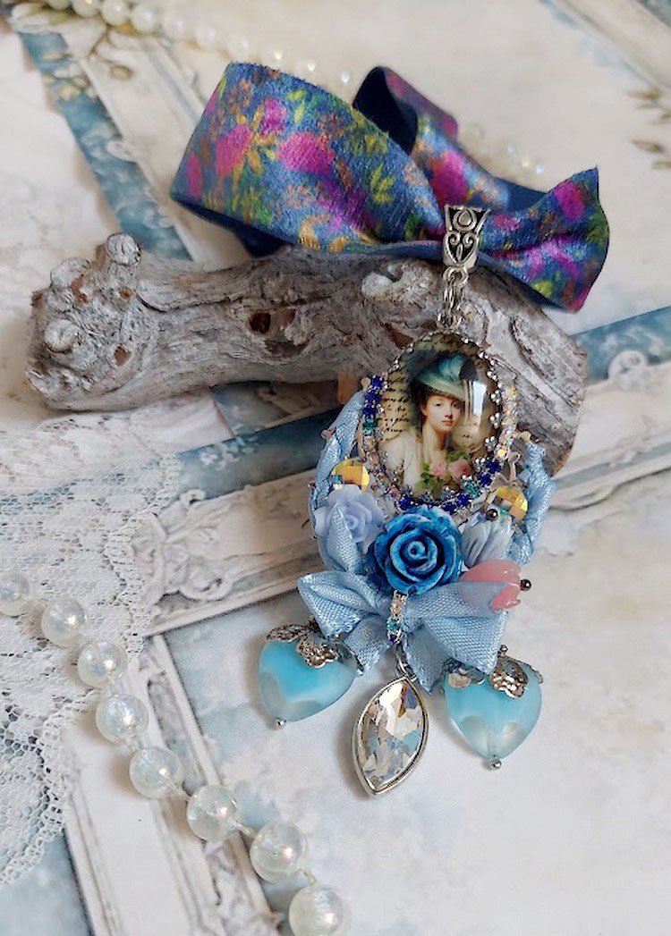 Pendentif Infiniment Bleuté créé avec fleurs synthétiques, résine, cabochon verre, ruban velours et perles Cristal Swarovski