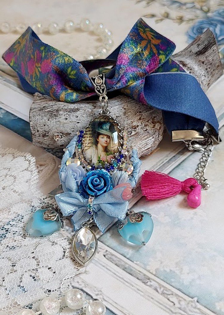 Pendentif Infiniment Bleuté créé avec fleurs synthétiques, résine, cabochon verre, ruban velours et perles Cristal Swarovski
