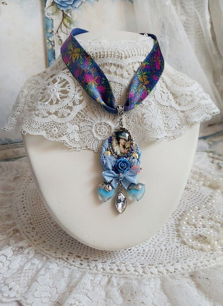 Pendentif Infiniment Bleuté créé avec fleurs synthétiques, résine, cabochon verre, ruban velours et perles Cristal Swarovski