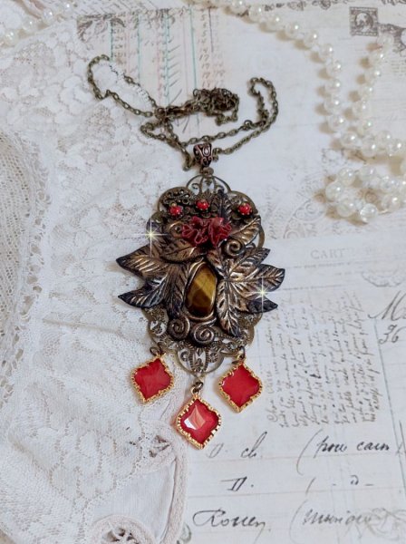Pendentif M&eacute;lodie avec un cabochon &OElig;il de tigre orn&eacute; de perles en Jade Rouge vein&eacute; de Noir sur fleurs 5 p&eacute;tales et estampes mont&eacute;s sur une cha&icirc;ne bronze. Les pendants sont en r&eacute;sine &eacute;poxy Rouge