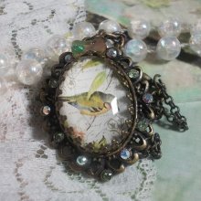 Gartenvogel-Halskette mit einem Lupen-Cabochon und Kristallen auf bronzefarbenen Accessoires.